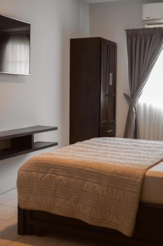 a bedroom with a bed and a cabinet and a window at Residencial Del Golf in La Lima