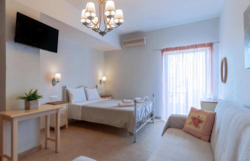 a bedroom with a bed and a tv and a couch at Kaiti 's Studios & Apartments in Palaiochóra