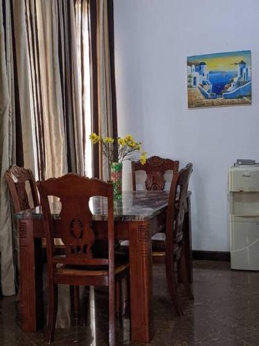 einem Esstisch mit Stühlen und einer Vase darauf in der Unterkunft Home sweet home in Daressalam