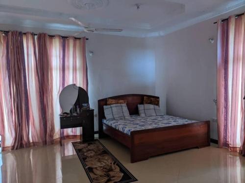 1 dormitorio con 1 cama en una habitación con cortinas en Home sweet home, en Dar es Salaam