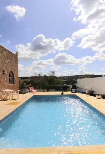 a large blue swimming pool next to a brick building at Villa chez NADA in Essaouira