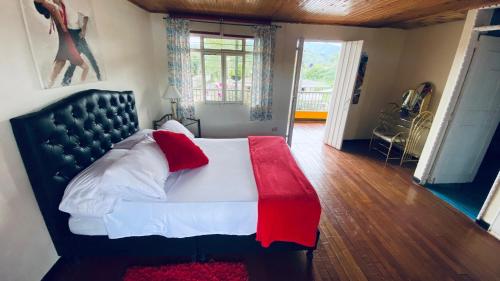 - une chambre avec un grand lit et une couverture rouge et blanche dans l'établissement Hospedaje Campestre Araucarias, à Santa Rosa de Cabal