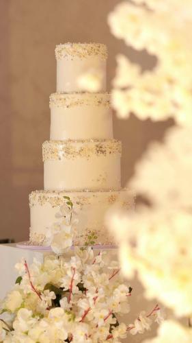 a three tiered white wedding cake with white flowers at Radisson Blu Hotel & Resort, Sohar in Sohar