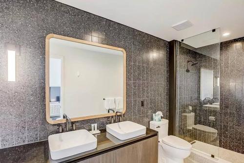 a bathroom with two sinks and a mirror and a toilet at Luxury Oasis on Rainy Street in Austin