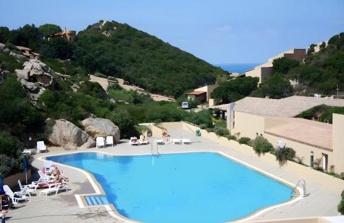 a large swimming pool with people sitting around it at Casa il Bouganville - sea view Costa Paradiso in Costa Paradiso