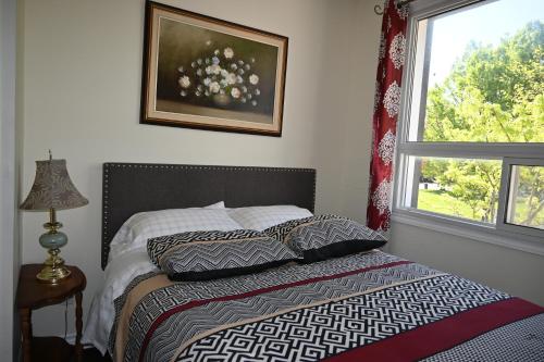 1 dormitorio con cama con almohadas y ventana en Centennial Suite, en Niagara Falls