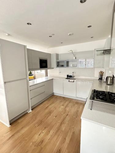 a white kitchen with white cabinets and a wooden floor at Spacious 4BR 4BA gated townhouse with balconies, Central JQ in Birmingham
