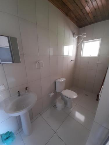 a white bathroom with a sink and a toilet at Pousada Ecológica Cavalo de Pedra in Peruíbe