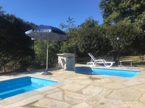 an umbrella and a swimming pool with a chair at Chalé Veredas e Buritis in Pirenópolis