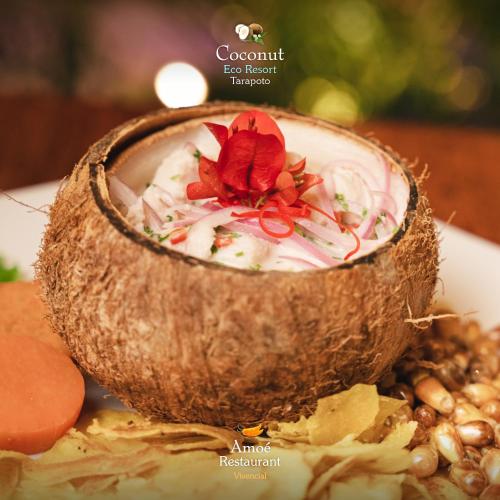 a bowl of coconut soup with a red flower in it at COCONUT TARAPOTO - ECO RESORT in Tarapoto