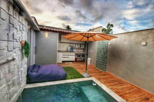 a swimming pool with an umbrella in a backyard at Villa Beija-Flor2: Suíte alexa e piscina privativa in Japaratinga