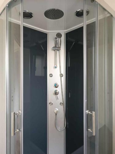 d'une douche avec des portes en verre et un pommeau de douche. dans l'établissement Maison neuve 3 chambres confortable au calme Nivillac Morbihan, à Nivillac