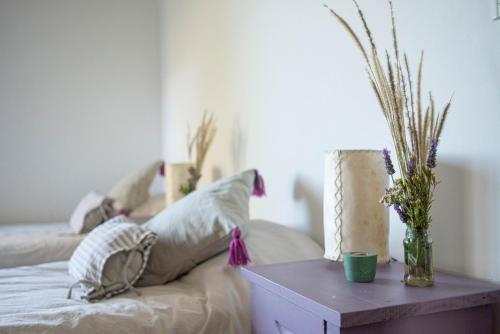 Una cama con almohadas y una mesa con flores. en Loma Puskana - Casas en Cachí