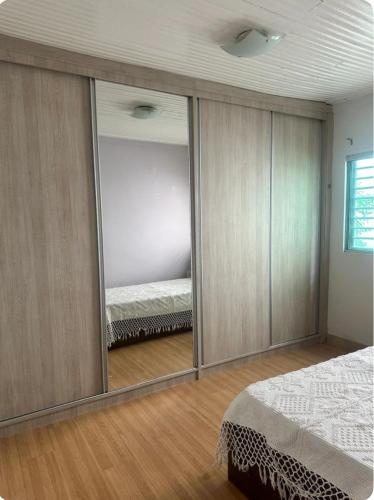 a bedroom with a large mirror and a bed at Casa aconchegante no centro in Divinópolis