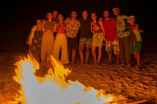 a group of people standing around a bonfire on the beach at Watu Kite House in Mayapo