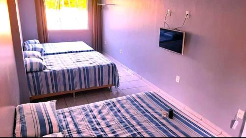 Pokój z dwoma łóżkami i telewizorem na ścianie w obiekcie Recanto Munik w mieście Palhoça