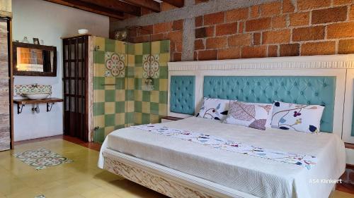 1 dormitorio con cama y pared de ladrillo en Villa Linda ApartaHotel, en Jericó