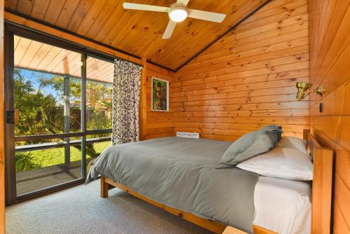 a bedroom with a bed in a wooden cabin at Cooper's Lakeside Cabin in Rotorua