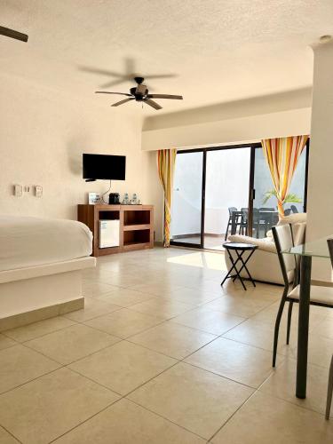a bedroom with a bed and a tv and a couch at Pelicano Inn Playa del Carmen - Beachfront Hotel in Playa del Carmen