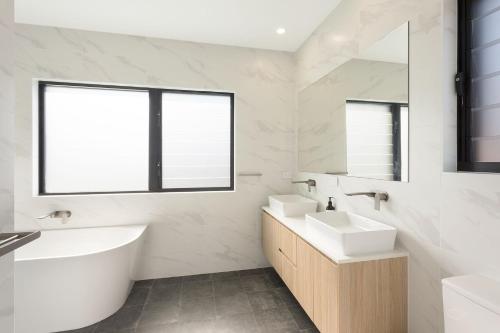 a bathroom with two sinks and a tub and a mirror at 6 Main Street "SouthWind" in Merimbula