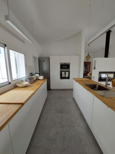 a kitchen with white cabinets and wooden counter tops at Casa Com Vagar in Campinho