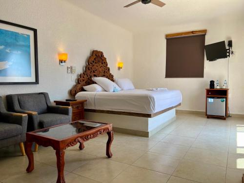 a hotel room with a bed and a couch and a table at Pelicano Inn Playa del Carmen - Beachfront Hotel in Playa del Carmen