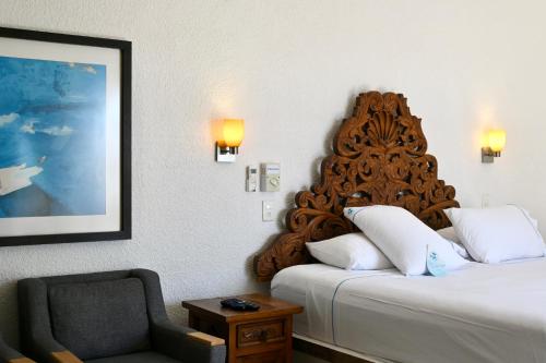 a hotel room with a bed and a chair at Pelicano Inn Playa del Carmen - Beachfront Hotel in Playa del Carmen