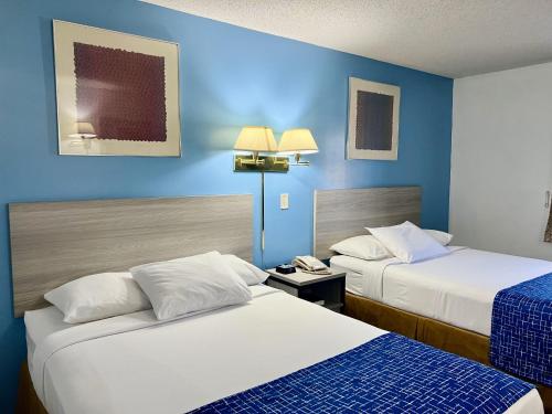 2 łóżka w pokoju hotelowym z niebieskimi ścianami w obiekcie Travelodge by Wyndham Hershey w mieście Hershey
