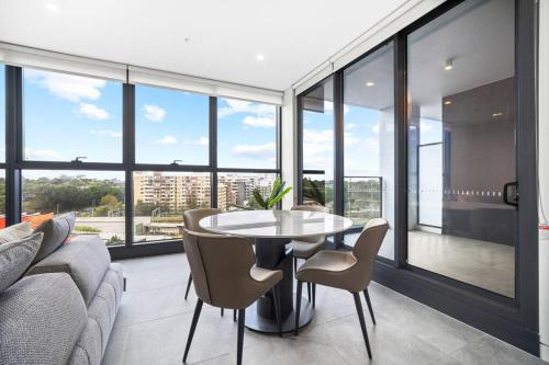 a table and chairs in a room with windows at Spacious 2Bedroom Apt in Homebush in Sydney