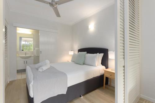 een witte slaapkamer met een bed en een wastafel bij Palm Villas in Port 6 in Port Douglas