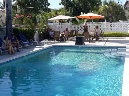 a swimming pool with people sitting in chairs and an umbrella at Sarah's Haven in Nassau