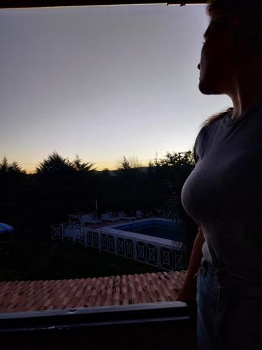 a pregnant woman looking out of a window at a pool at Complejo Cantonavi in Mina Clavero