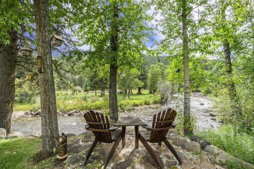 a table and two chairs sitting next to a river at Three-Bedroom Apartment in Estes Park