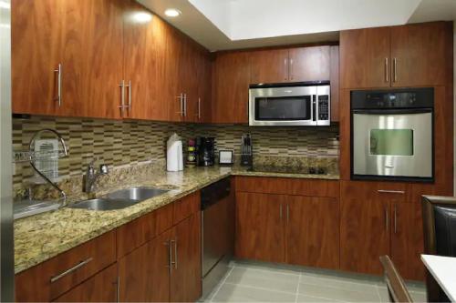 a kitchen with wooden cabinets and stainless steel appliances at Oceanfront Condo - Ocean Views, Pool, Gym Hollywood Beach in Hollywood