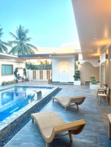 a swimming pool with two lounge chairs next to a building at Villa De Phawa in Samut Songkhram