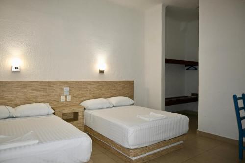 a room with two beds and a mirror at Pelicano Inn Playa del Carmen - Beachfront Hotel in Playa del Carmen