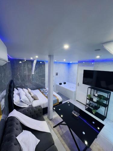 a bedroom with a couch and a tv and a tub at Room & Jacuzzi - Stade de France in Saint-Denis