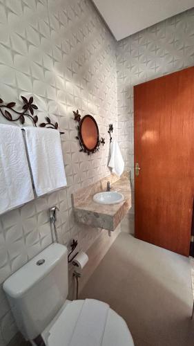 a bathroom with a white toilet and a sink at Pousada Estrelar in Lençóis