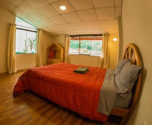 ein Schlafzimmer mit einem Bett mit einer orangefarbenen Bettdecke in der Unterkunft Cozy central apartment with mountain view in Pisac