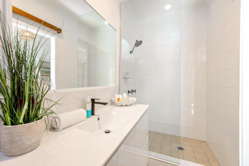 a white bathroom with a sink and a shower at Palm Cove Beach Retreat - 1st Floor in Palm Cove