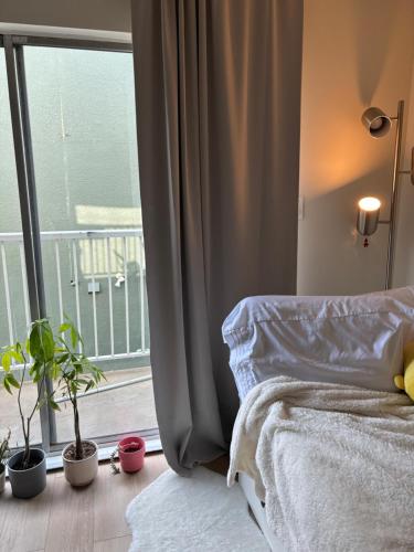 Cosy Living: Your Private Urban Retreat في فانكوفر: غرفة نوم مع سرير ونافذة مع نباتات الفخار