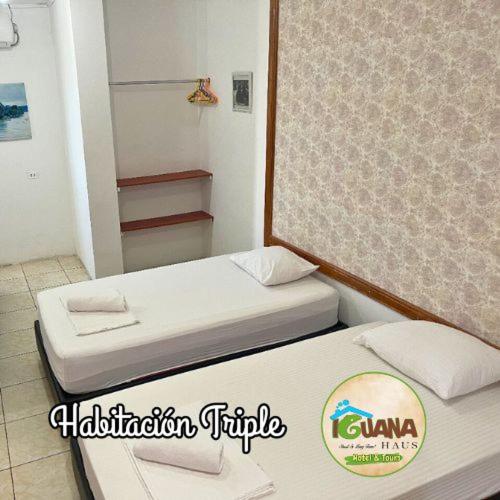 two beds in a small room with a mirror at IGUANA HAUS IQUITOS in Iquitos
