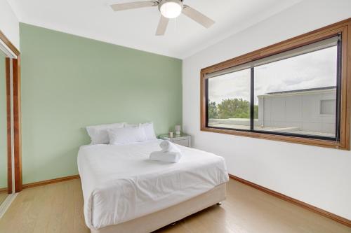 sypialnia z białym łóżkiem i dużym oknem w obiekcie Hope Island Haven Retreat w mieście Gold Coast