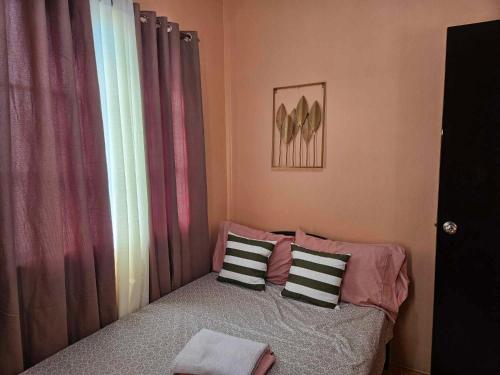 - une chambre avec un lit avec deux oreillers et une fenêtre dans l'établissement Mel's Place 2BR Apartment Unit1 in Batangas City, à Batangas City