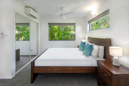 Heliconia Grove - 1 bedroom - on Hamilton Island by HIHA في جزيرة هاميلتون: غرفة نوم بسرير كبير ونوافذ