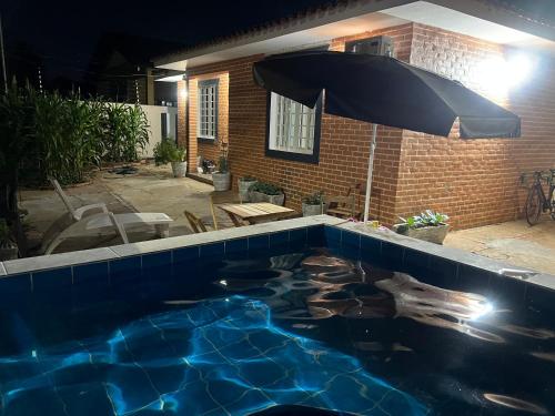 uma piscina com um guarda-sol e alguns peixes nela em Suíte Príncipe Charles Ceres0021 em Cuiabá