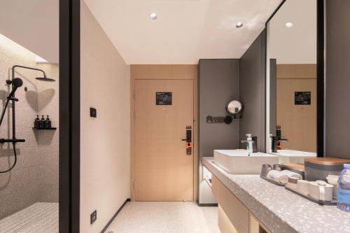 een badkamer met een wastafel, een douche en een spiegel bij Atour S Hotel Ningbo Heyi Avenue in Ningbo