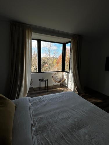 a bedroom with a bed and a large window at Casa Raíz Cumbrecita in La Cumbrecita