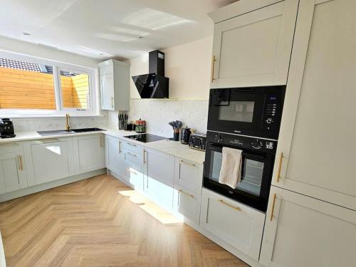 una cocina con armarios blancos y electrodomésticos negros en Newly Renovated Gem - Free Parking & Modern Comfort en Glasgow