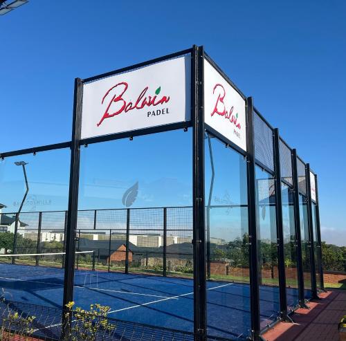 un court de tennis avec un panneau indiquant l'hôtel dans l'établissement Ballito Splash, à Ballito